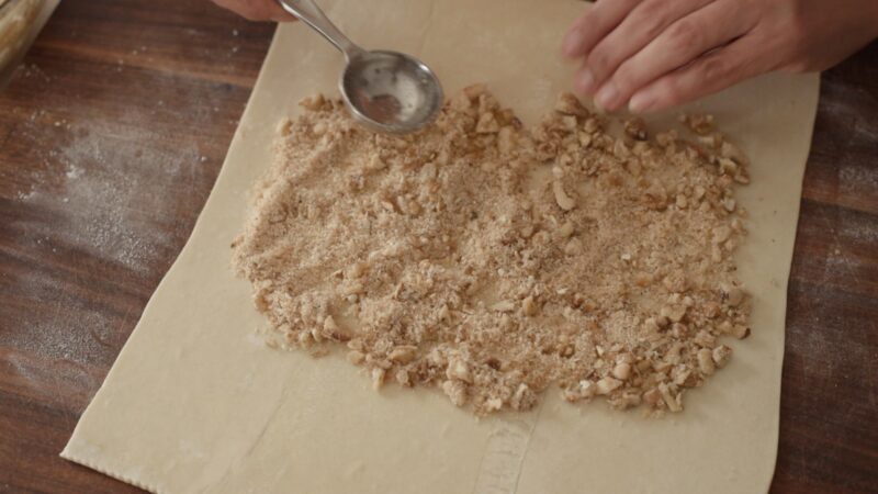 Breadcrumb mixture is spread on a piece of puff pastry.