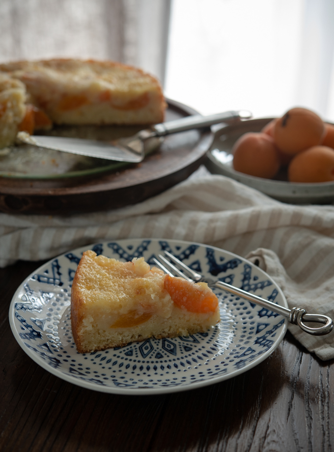 A slice of apricot Kuchen (German apricot cake) is served on a plate