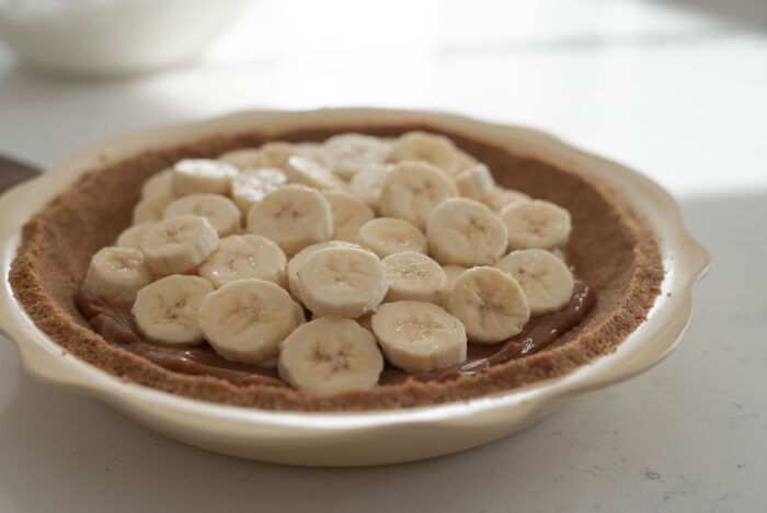 Banana slices are on top of graham cookie crusted pie dish
