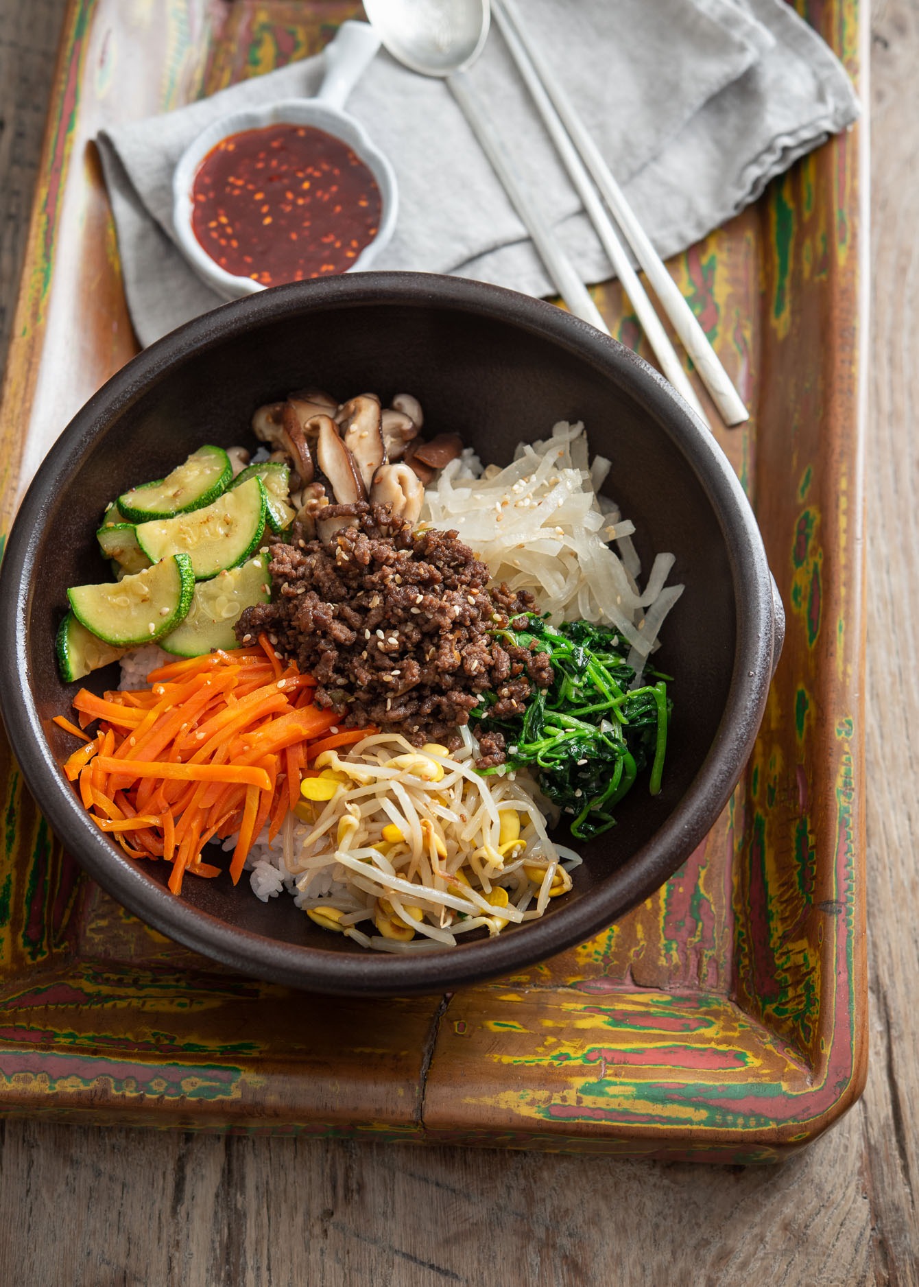 Bibimbap, Korean rice bowl, arranged with colorful vegetables and ground beef bulgogi over rice.