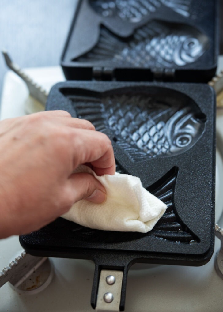 Greasing the fish shaped mold with an oiled kitchen paper towel.
