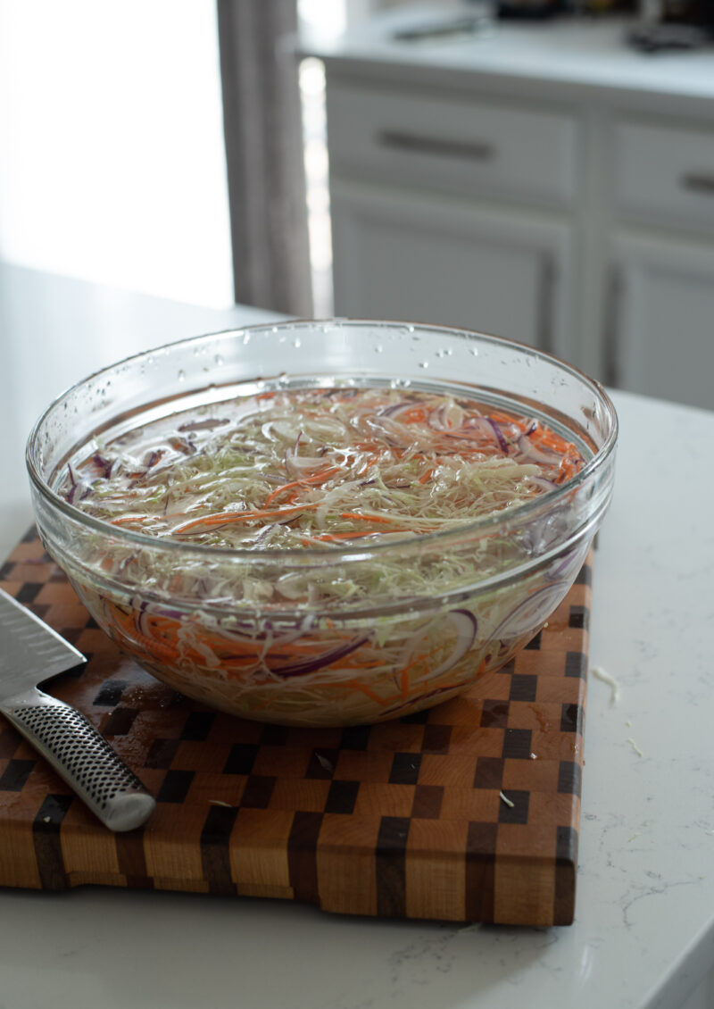 Shredded cabbage, carrot, and onion soaking in cold water for crispy Vietnamese chicken salad.
