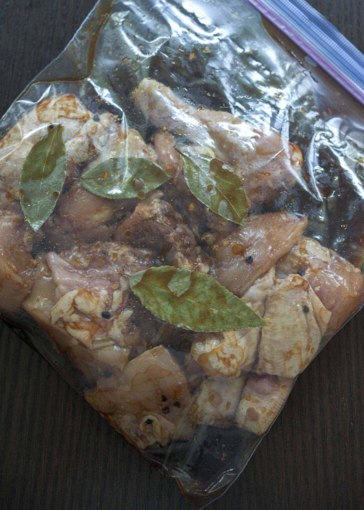 Chicken pieces marinating with Filipino adobo sauce in a zip bag.
