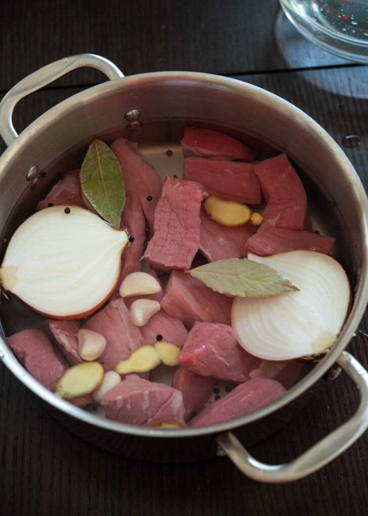 Beef chunks and aromatic vegetables in a pot.