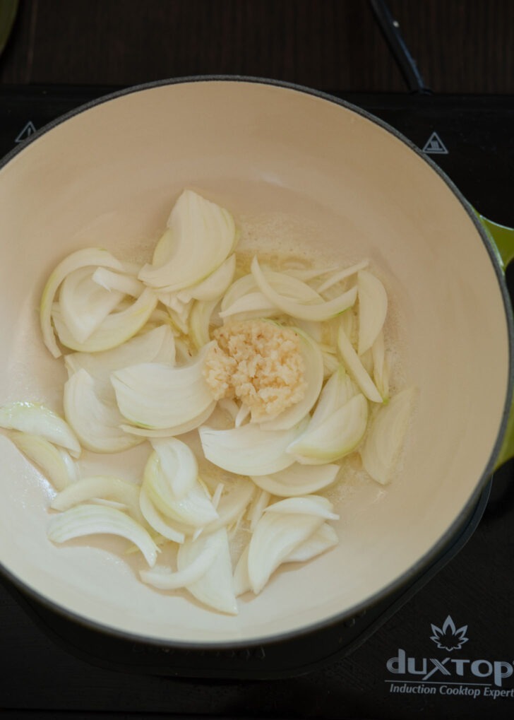 Onion and garlic added in hot butter in a soup pot.