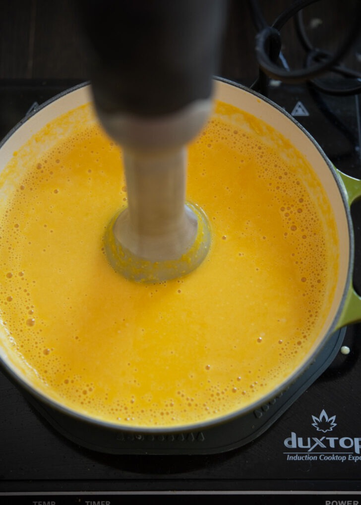 Immersion blender pureeing kabocha soup in a soup pot.