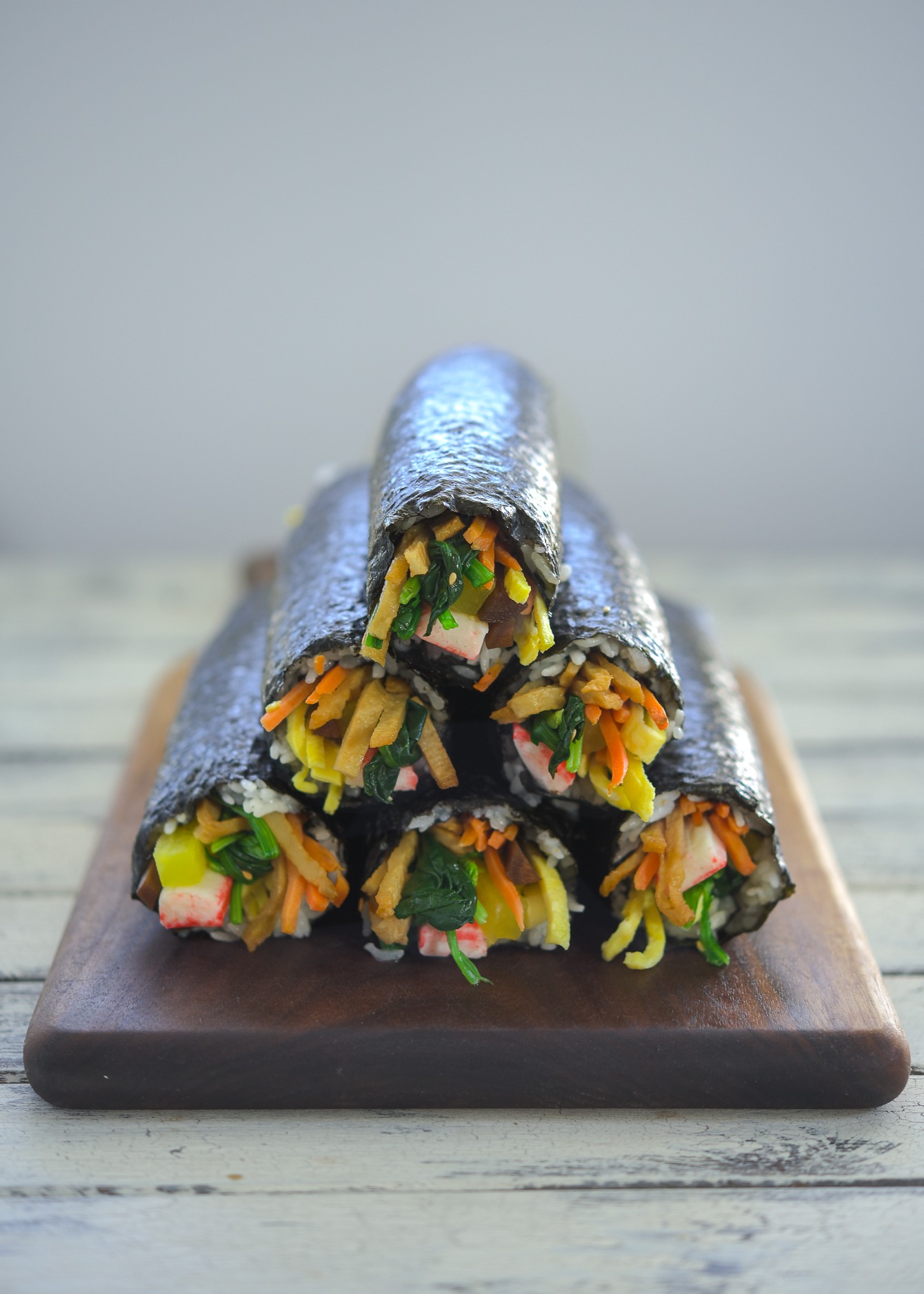 Kimbap (Korean seaweed rice rolls) or gimbap stacked together on a wooden board.