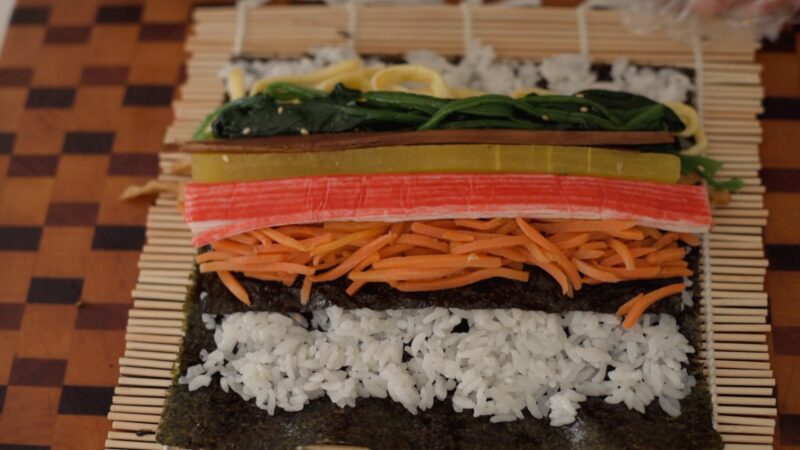 Kimbap fillings are placed on the rice over seaweed.