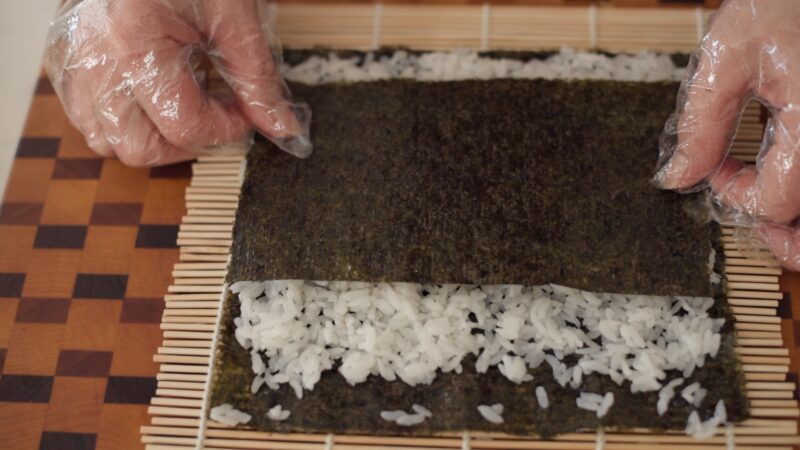Another layer of seaweed is placed on top of rice.