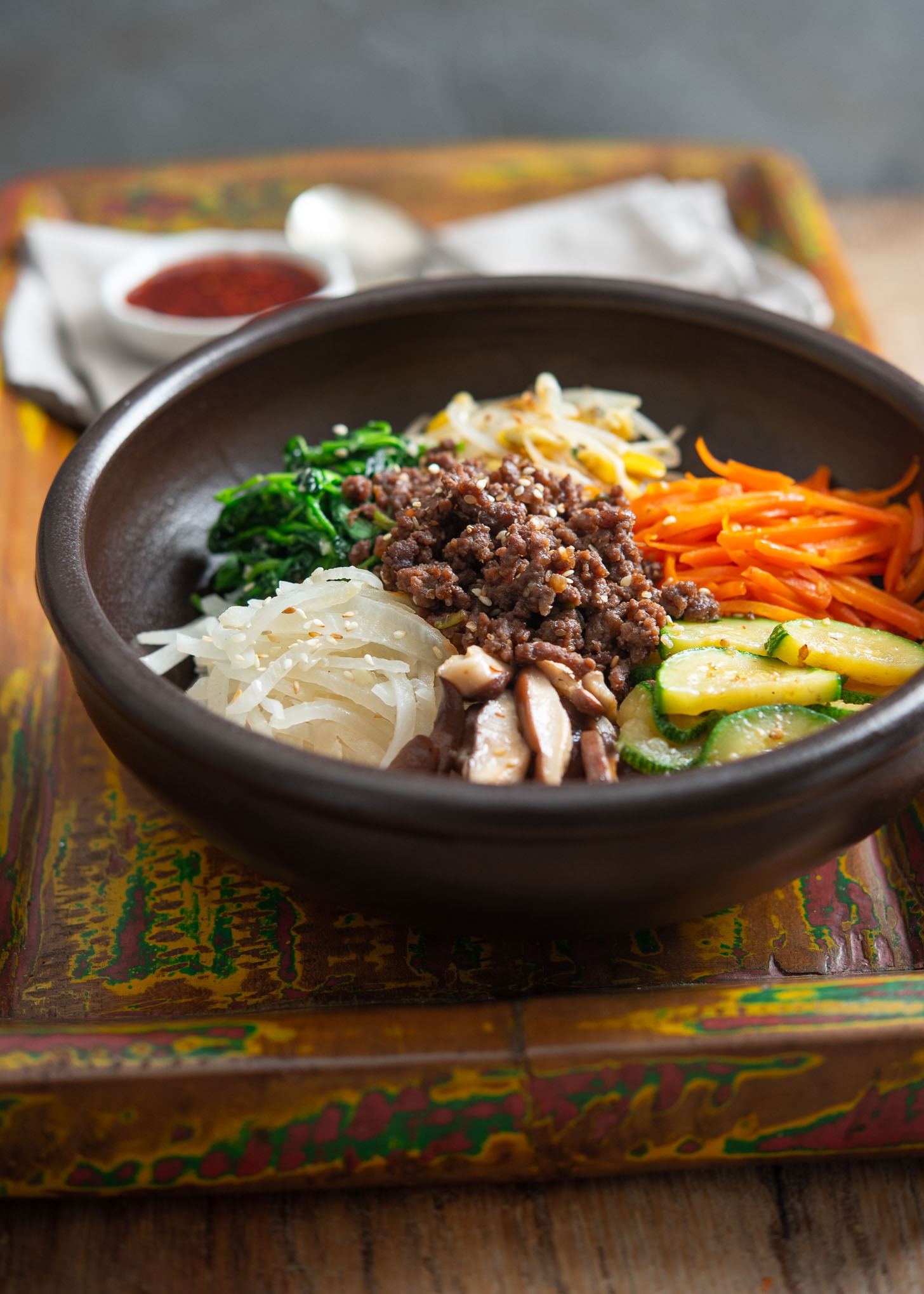 A bibimbap bowl assembled with ground beef bulgogi and colorful Korean vegetables.