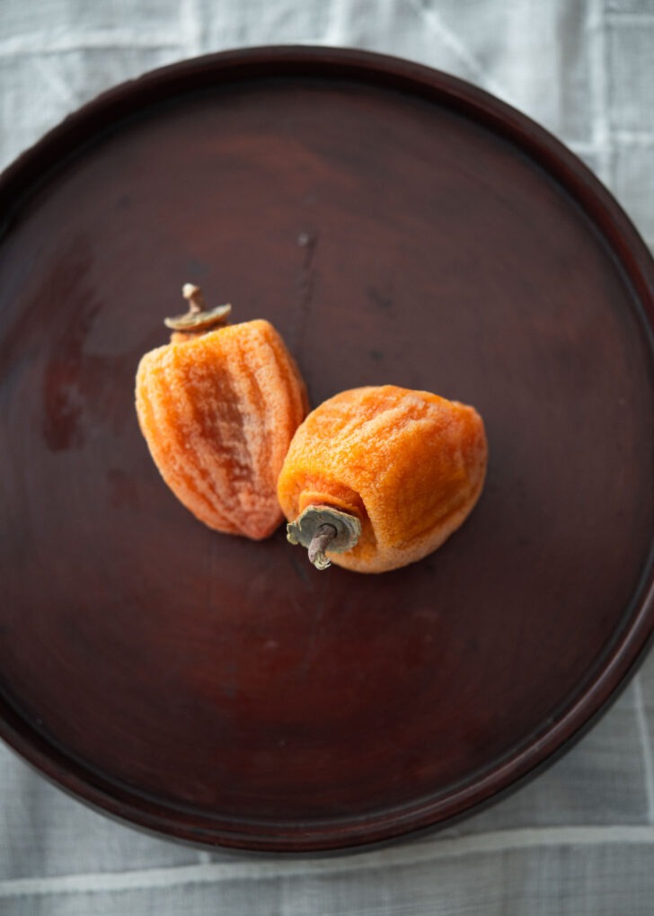 Two dried persimmon is showing their deep orange color.