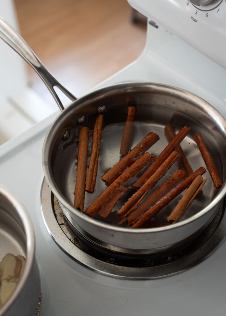 A bunch of cinnamon sticks are simmering in a pot of water.