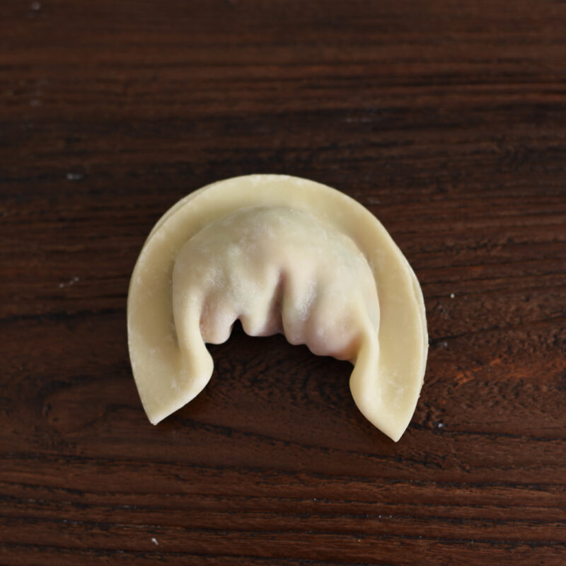 The both ends of dumpling wrapper are bend down toward the center.