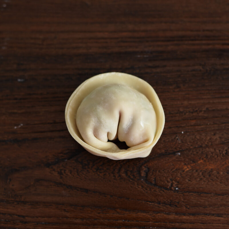 The ends of filled dumpling wrapper are pinched together creating a moon shape mandu.