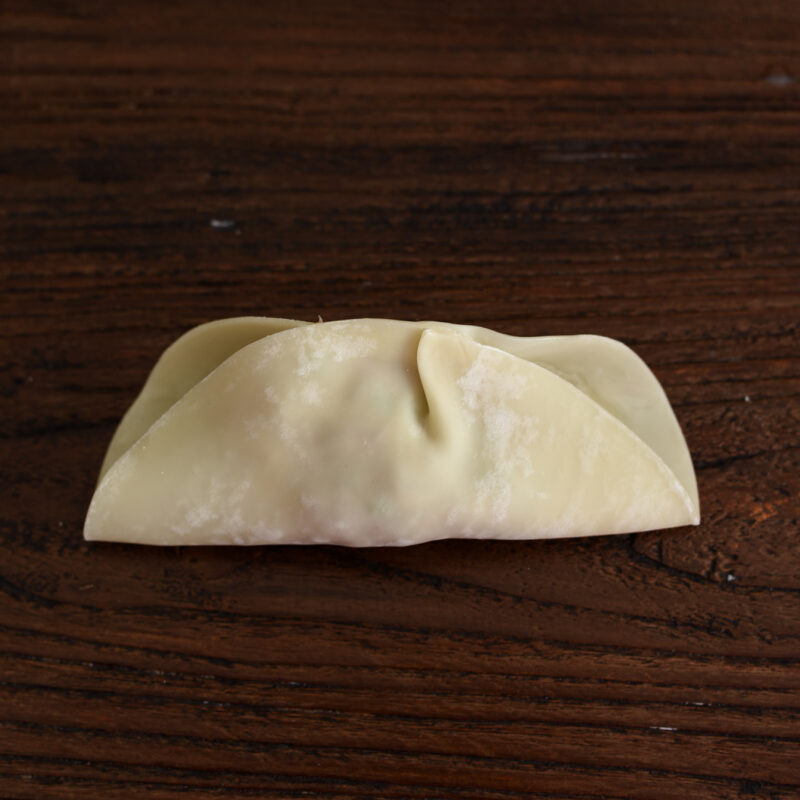 Filled dumpling is folded in half to make mandu.