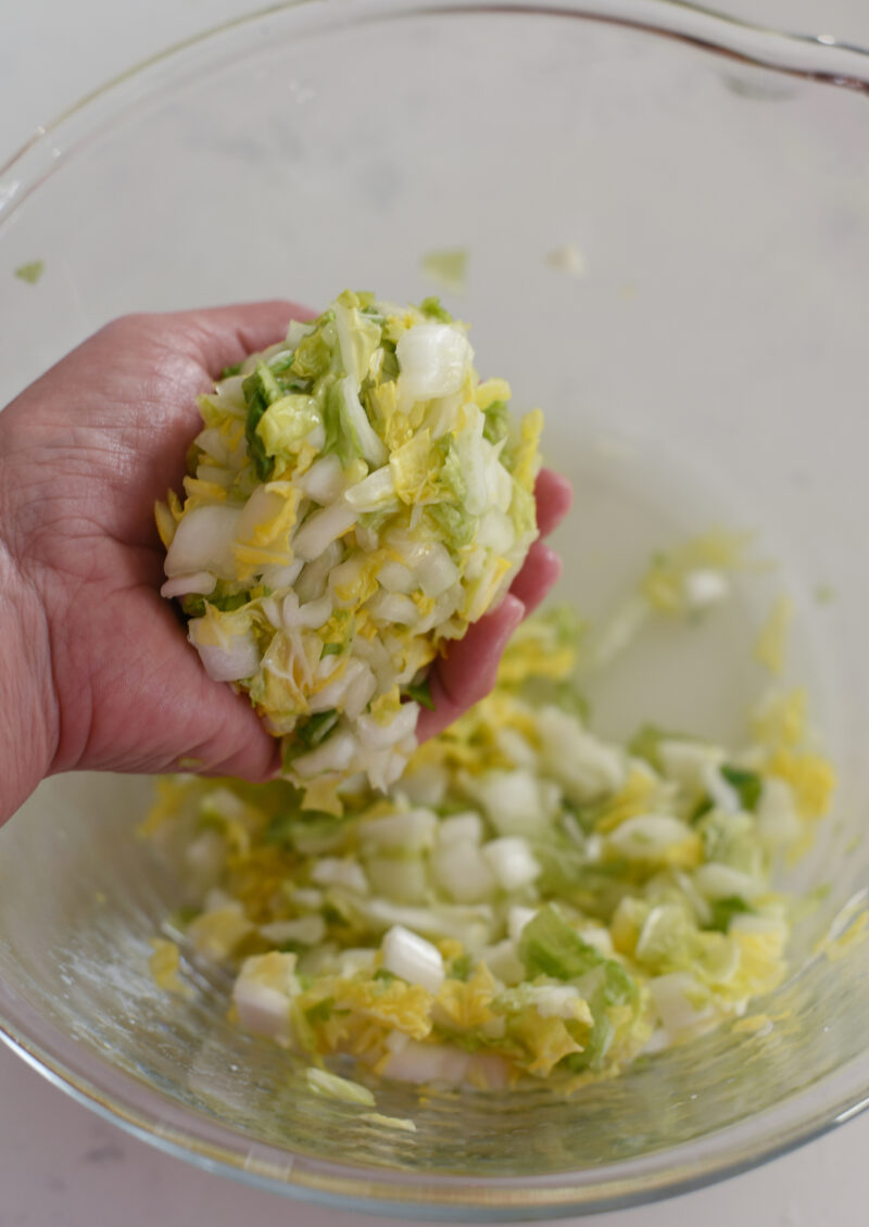 Salted cabbage pieces are squeezed out to remove excess water.