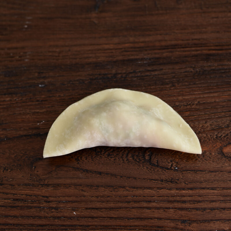 Filled dumpling wrapper is folded in half.