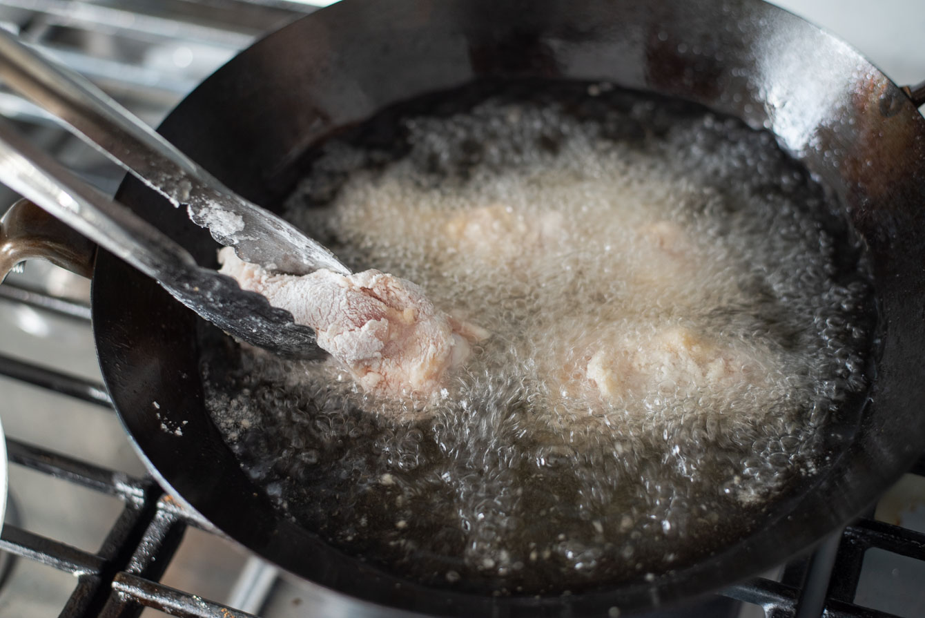 Deep frying chicken wings in hot oil.