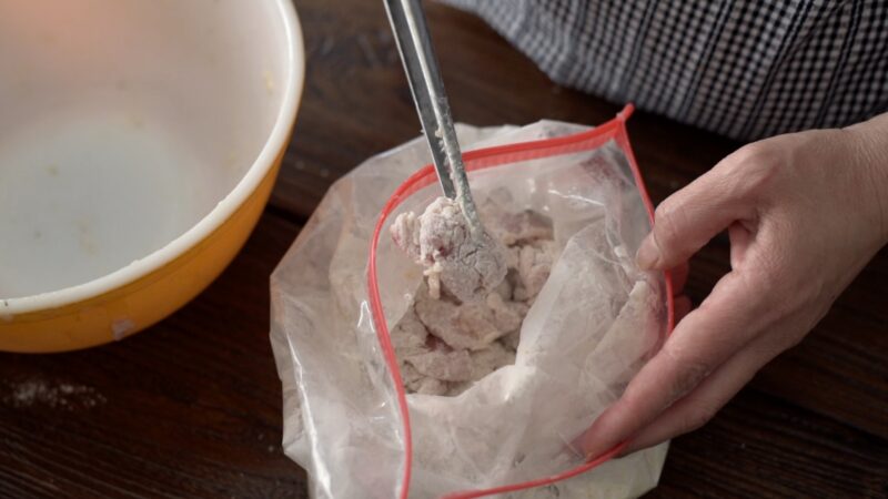 Chicken and coating mixture are put inside a zip bag and shake to coat evenly.