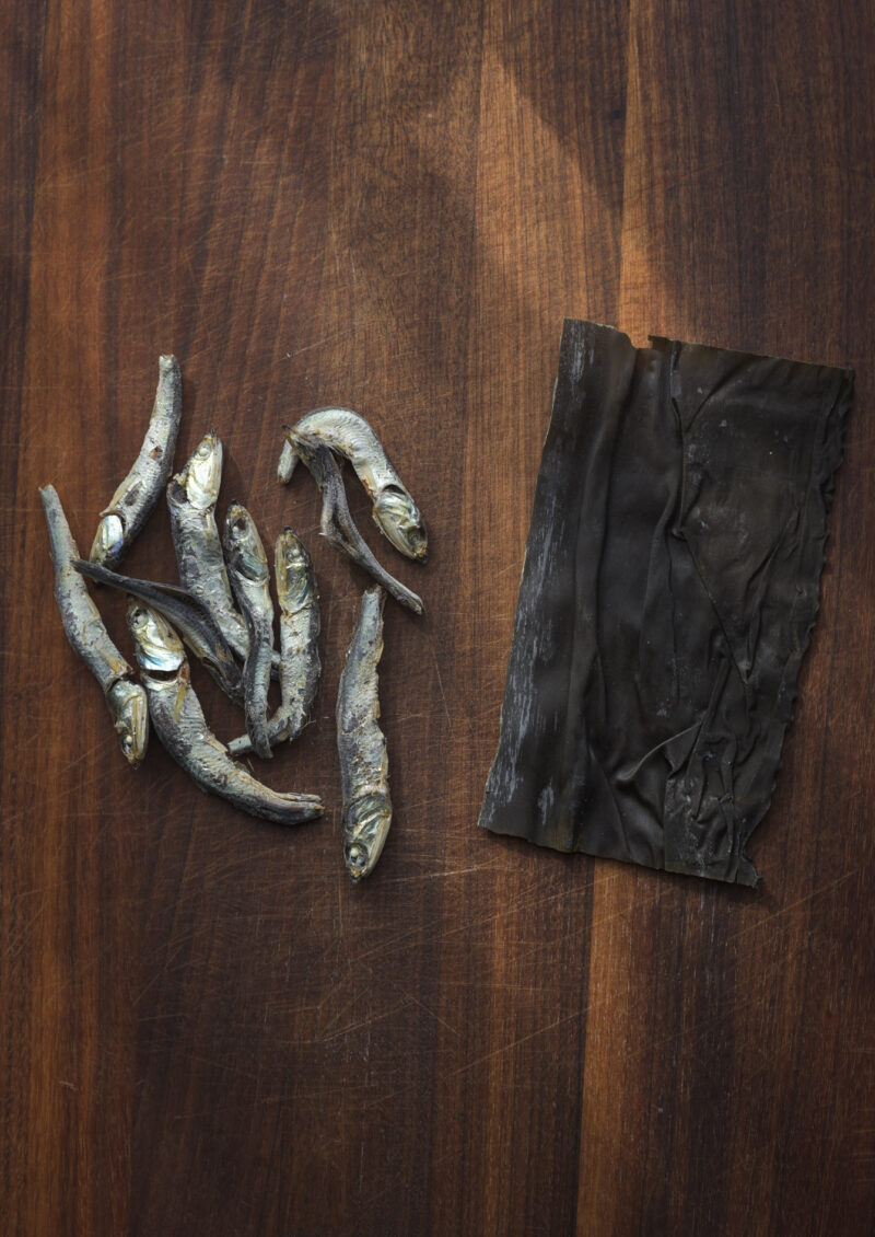 Dried anchovies and dried sea kelp are displaying on the wooden board.