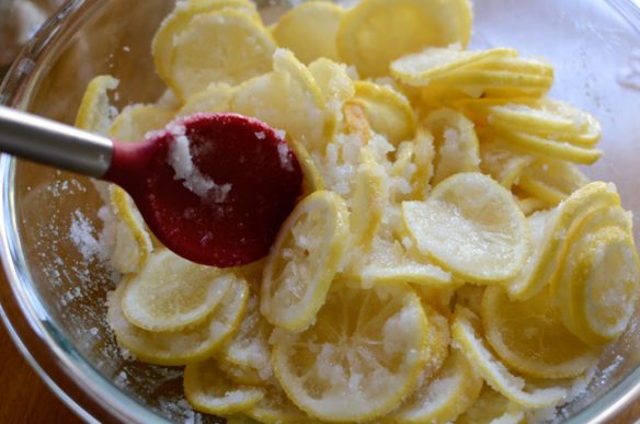 lemon slices are tossing with sugar in a bowl.