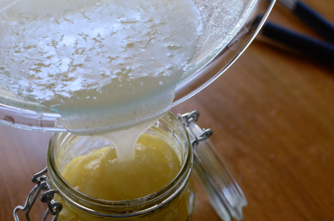 Extra sugar syrup remains are pouring into the glass jar with lemon in it.