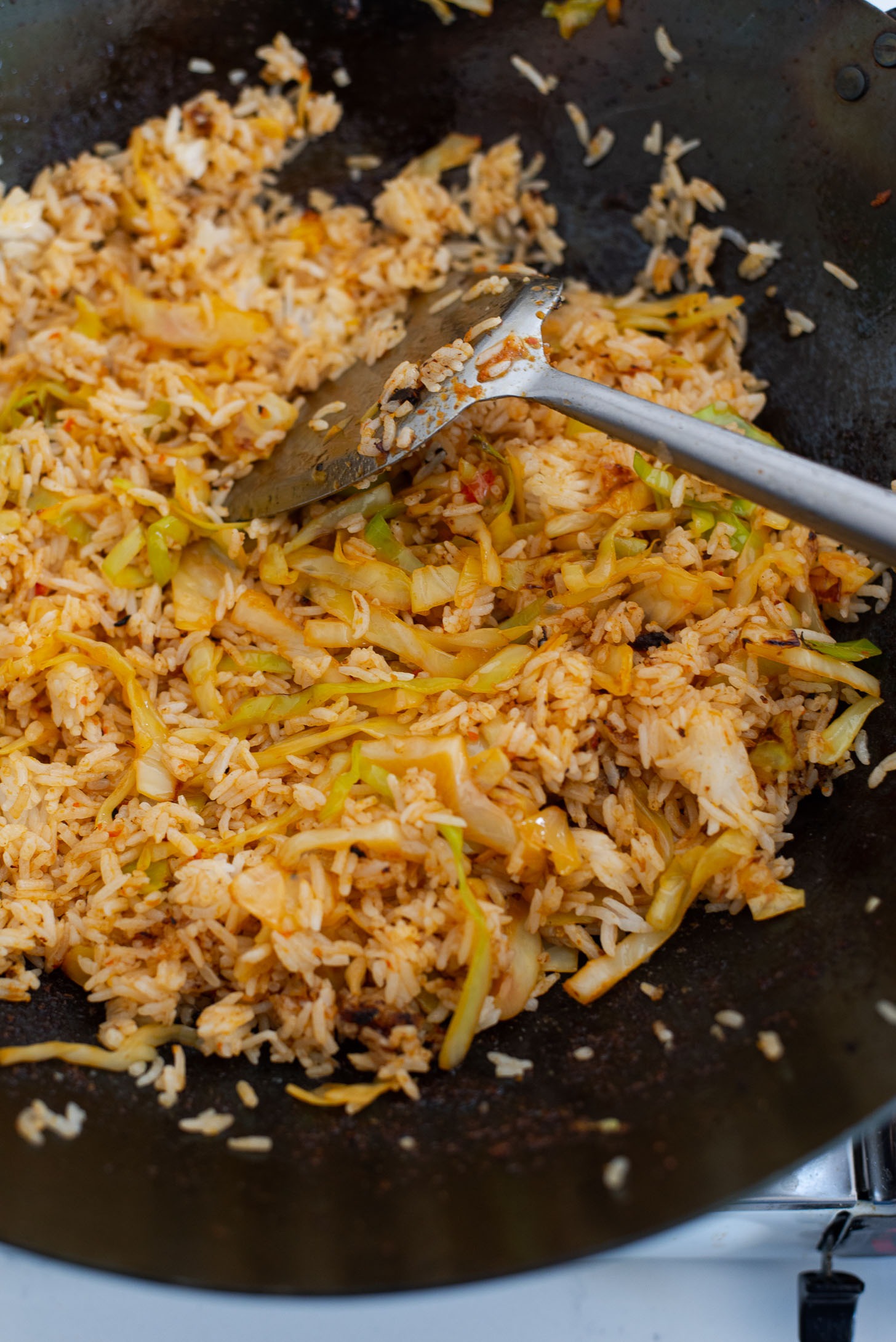 Rice is added to vegetable mixture in a wok to make Nasi Goreng.