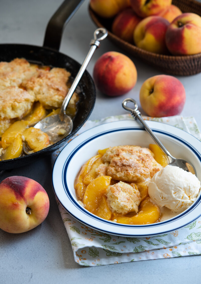 Biscuit topped classic peach cobbler served with ice cream.