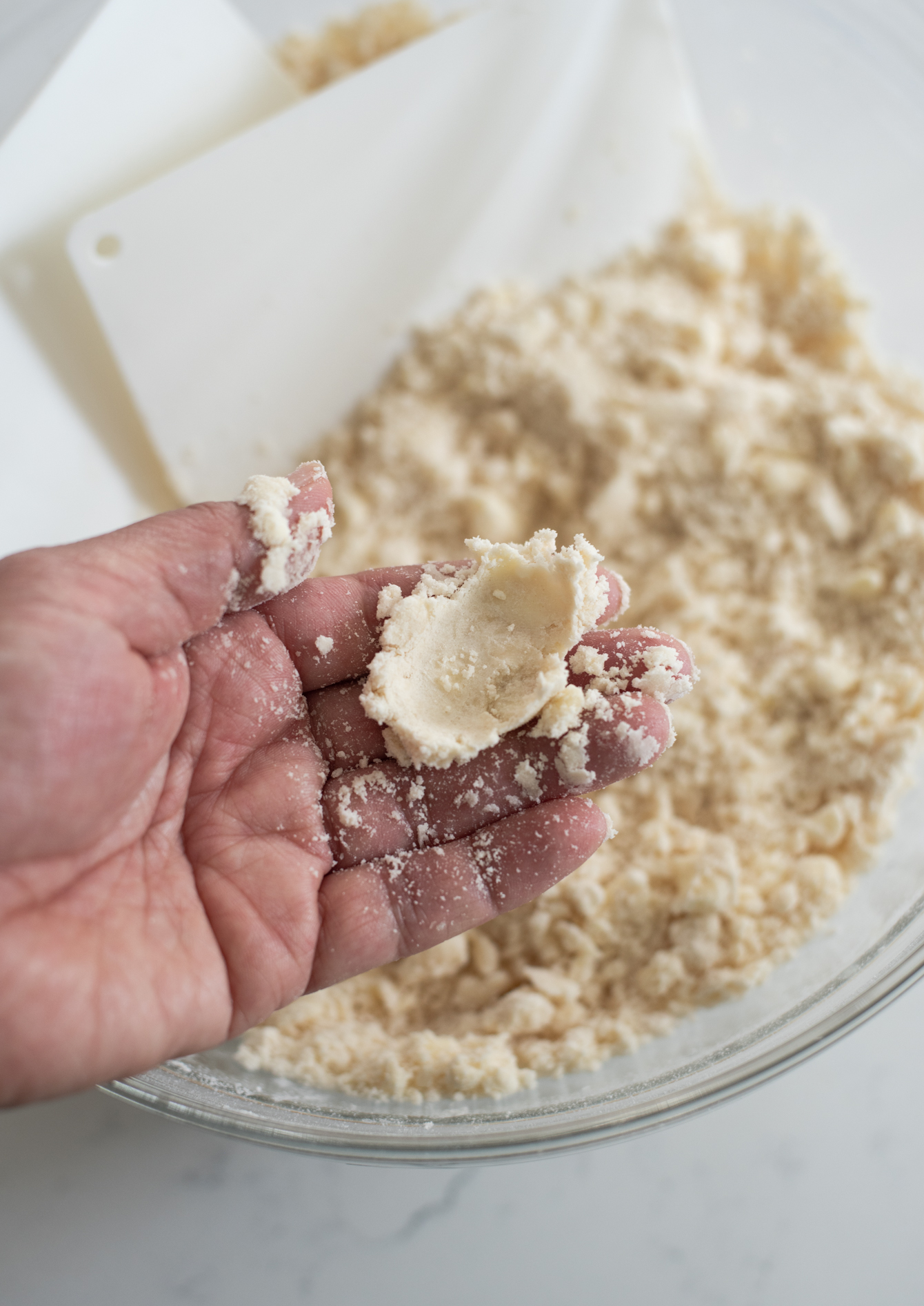 Pressing dry pie dough with fingers to see it holds together.