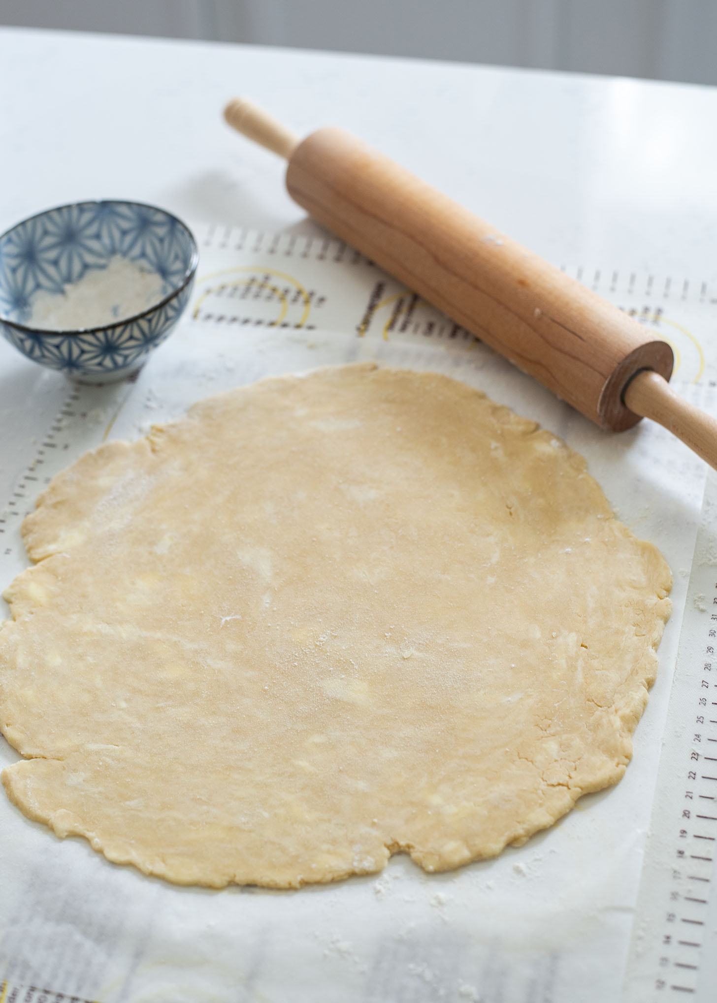 Homemade pie dough is rolled out with a rolling pin