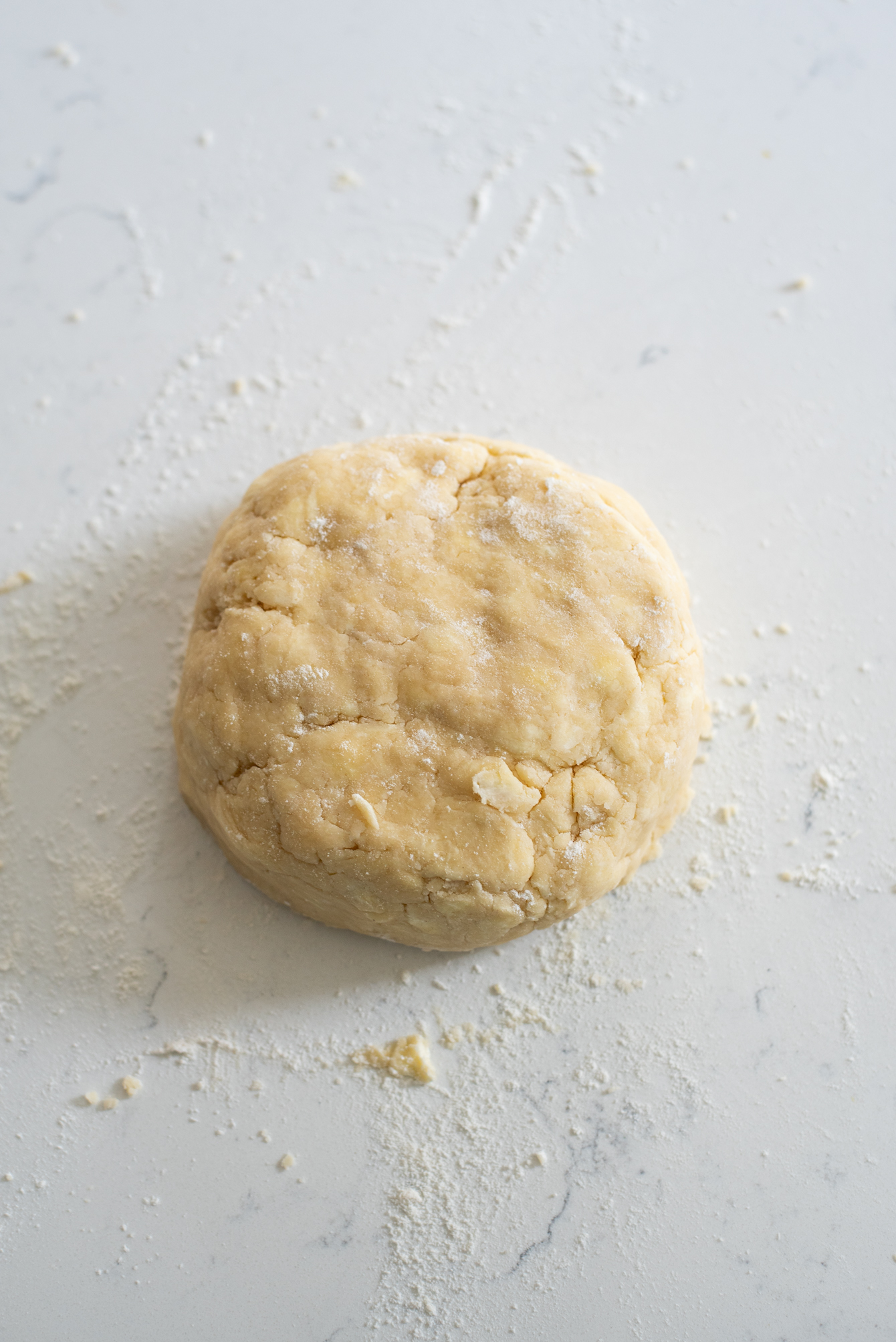 Lard and butter Pie dough is gathered to form a disk shape.