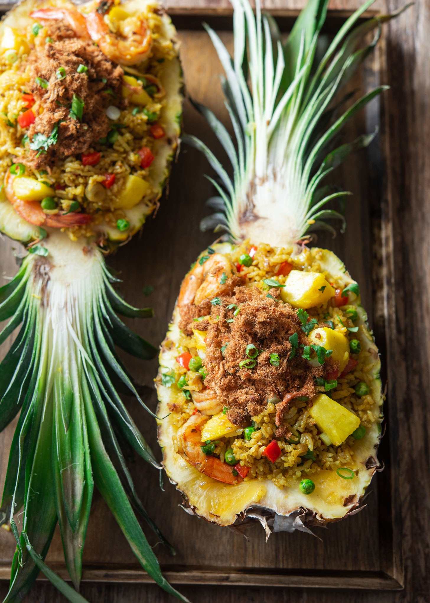 Pineapple fried rice is served in two pineapple boats topped with pork floss.