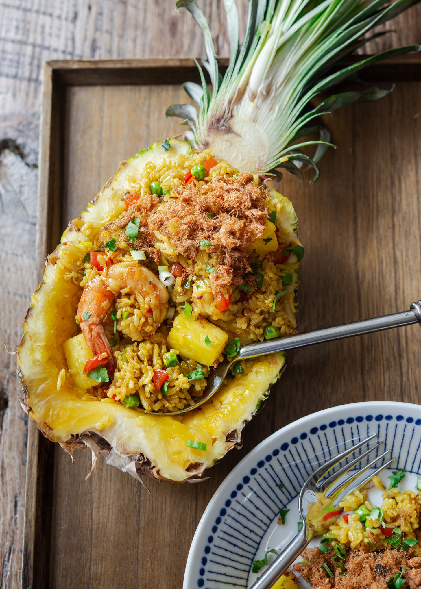 Thai Pineapple fried rice served in a fresh pineapple boat with a spoon.