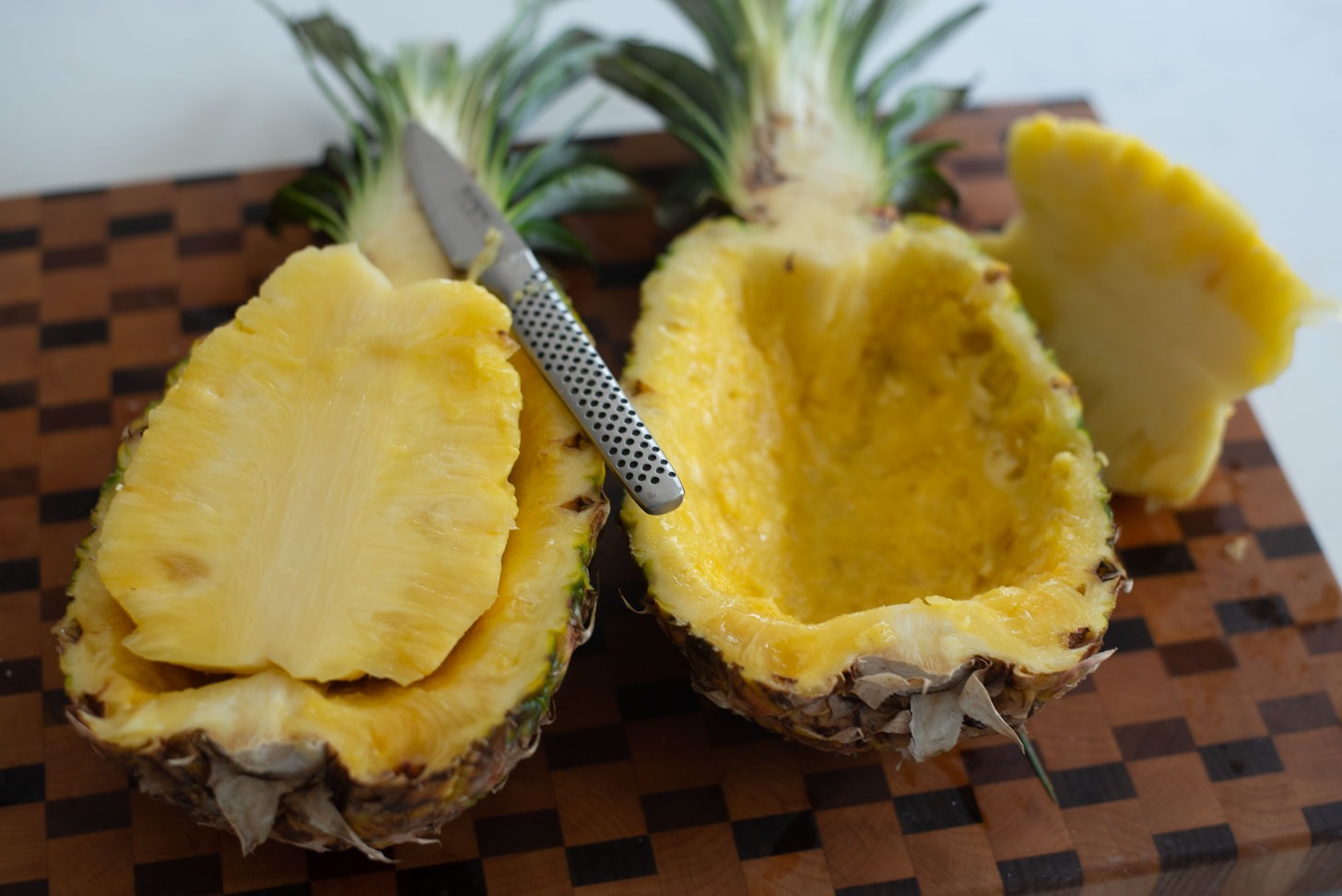 A whole pineapple is cut in half and the flesh in the center is carved.