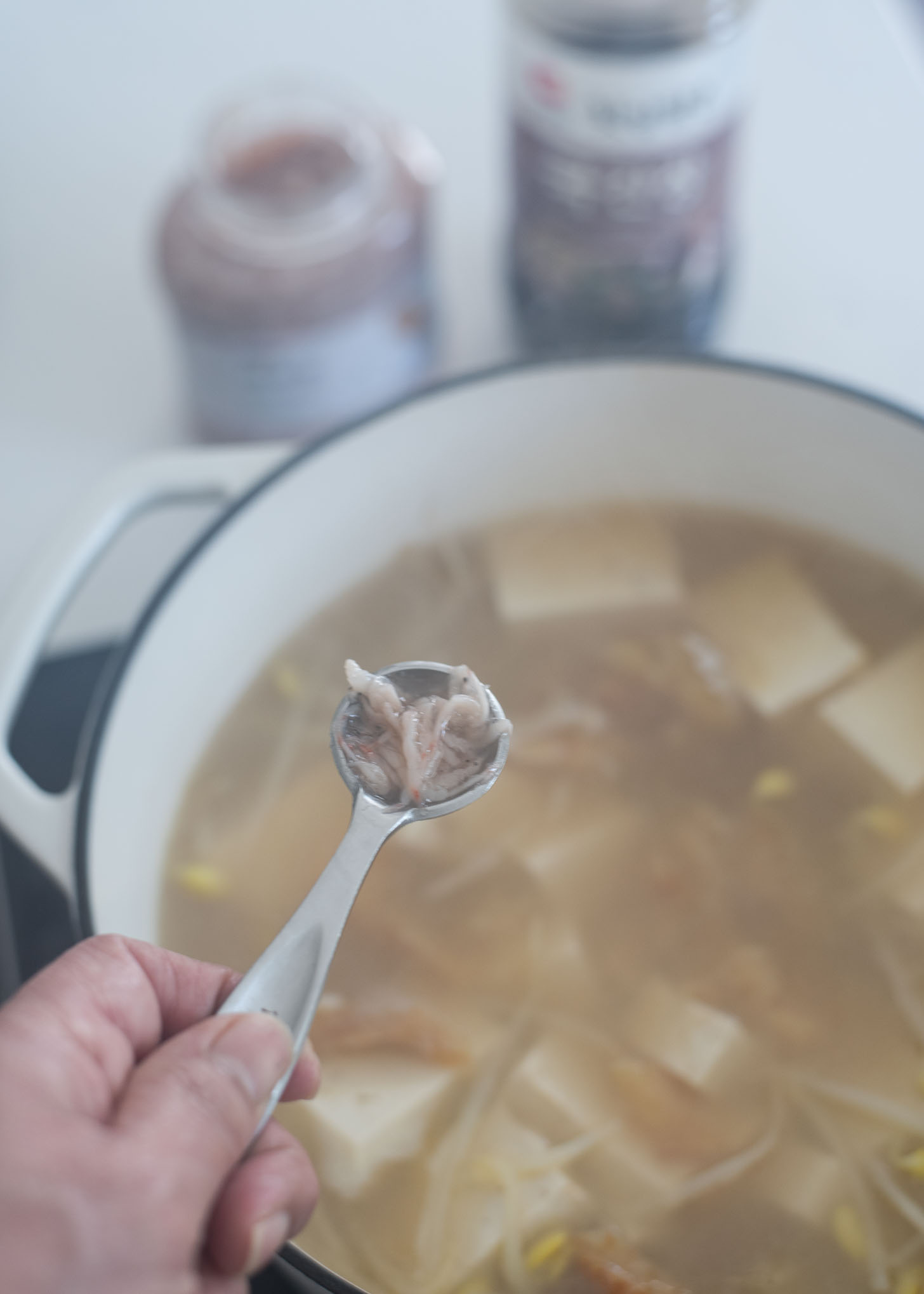 Korean shrimp sauce is added to pollock soup in a pot.