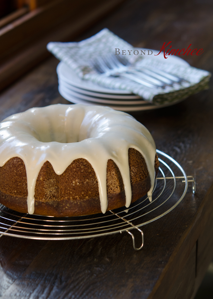 Cream cheese glazed pumpkin bundt cake on a wired rack and plates to serve with.