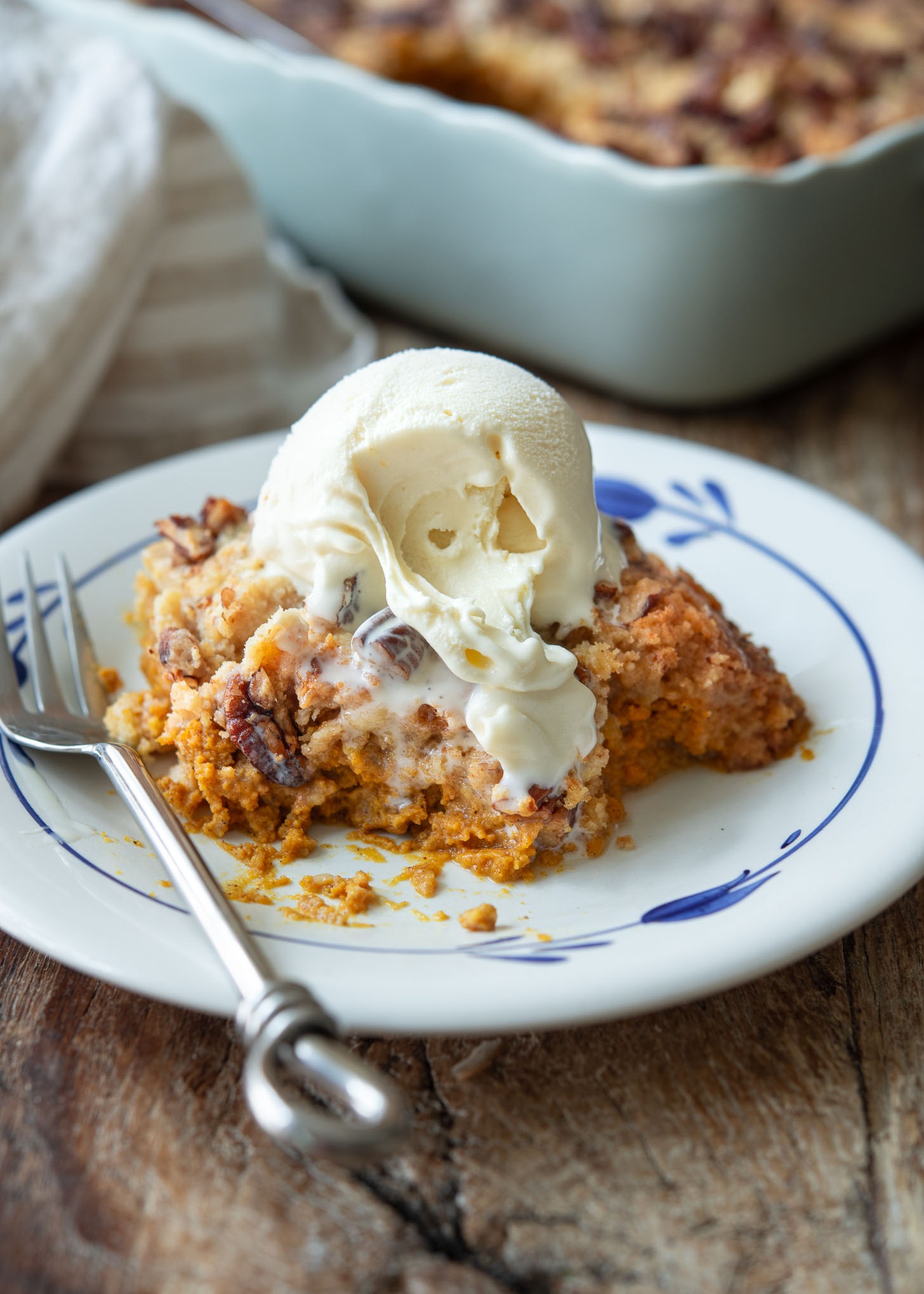 A plate of pumpkin pie crunch topped with ice cream.