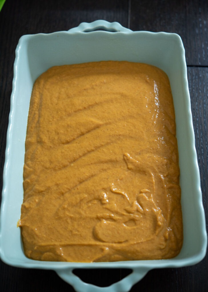 Pumpkin pie filling layer placed in a baking pan.