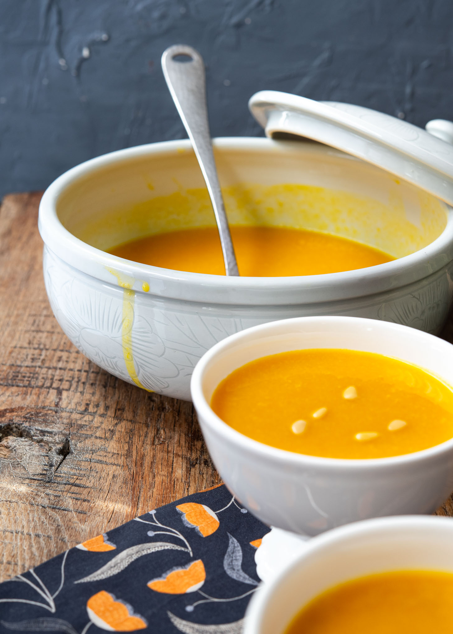 A large soup bowl and serving bowls are filled with Korean pumpkin porridge (hobakjuk).