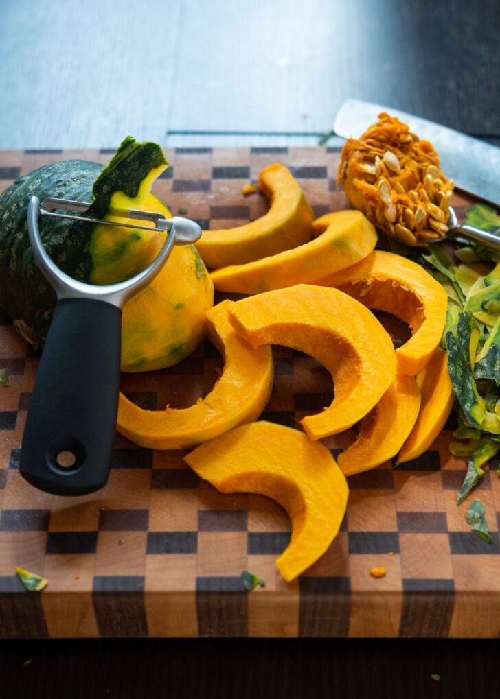 Kabocha pumpkin peeled and sliced on a cutting board.,