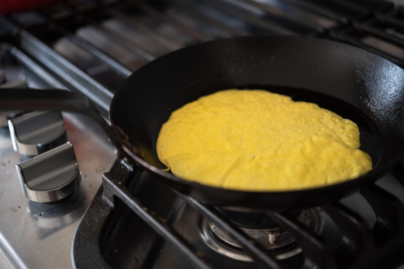 Beaten egg yolk is thinly spreader and cooked in a skillet.