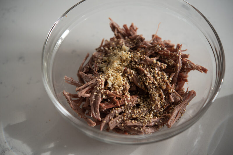 Beef is shredded and seasoned separately before adding to the rice cake soup.