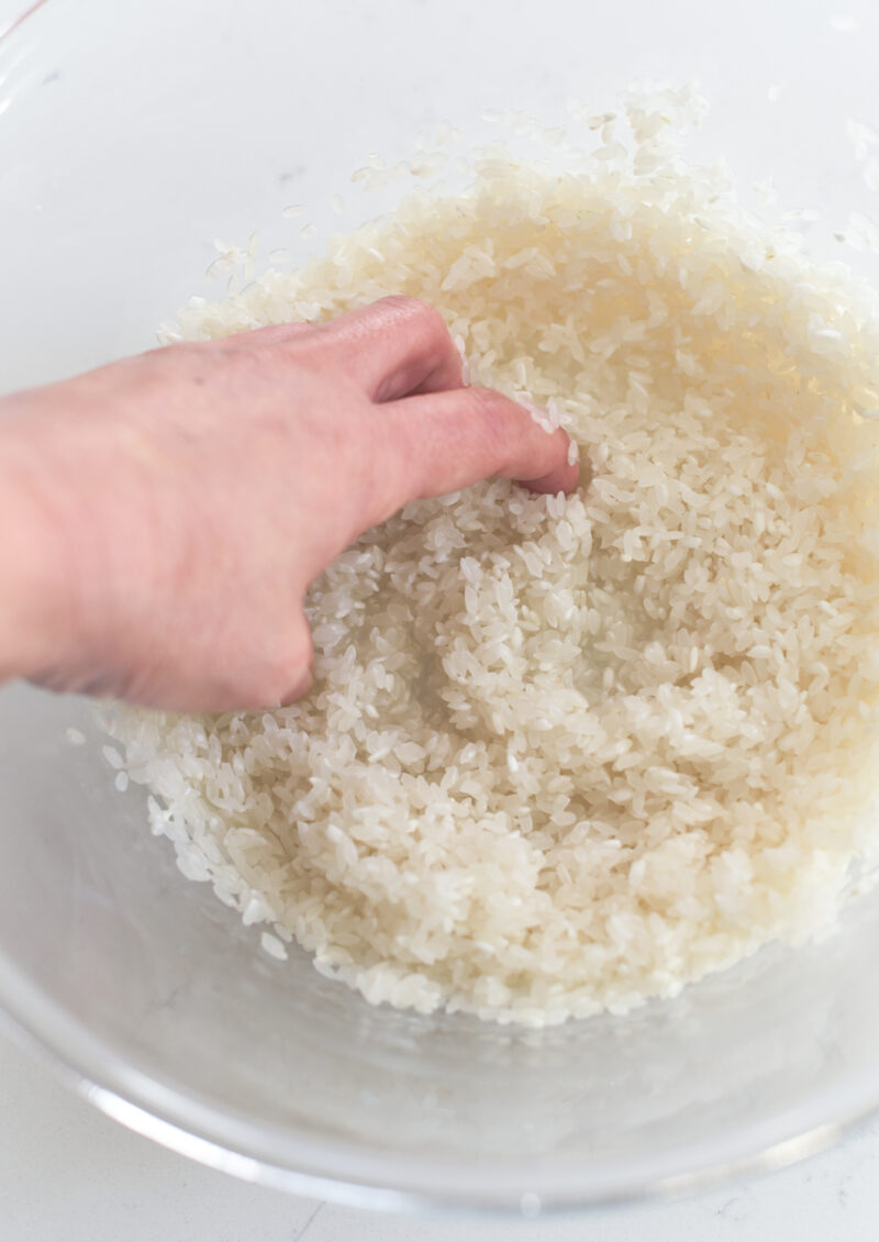A hand is swirling the rice in a.bowl.