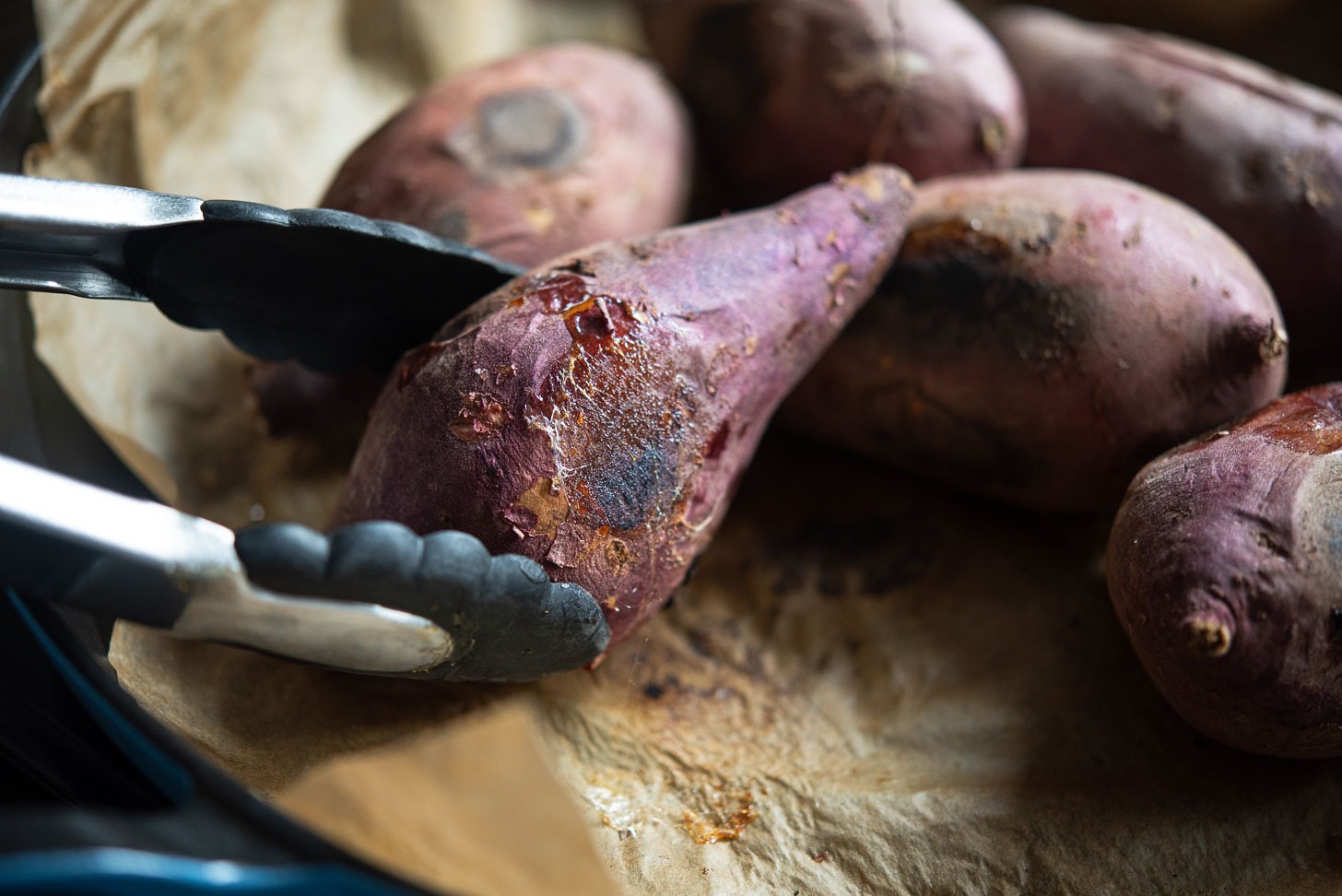 Turn pan roasted Korean sweet potato to the other side using a kitchen tongs