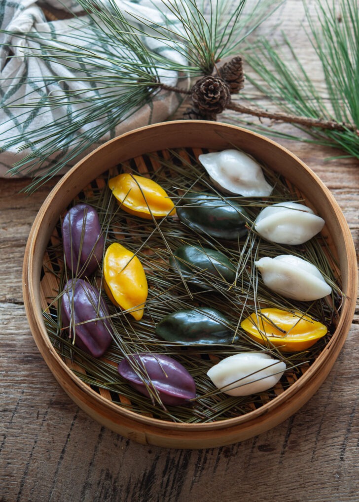 Colorful Songpyeon steamed over pine needles in a bamboo basket.