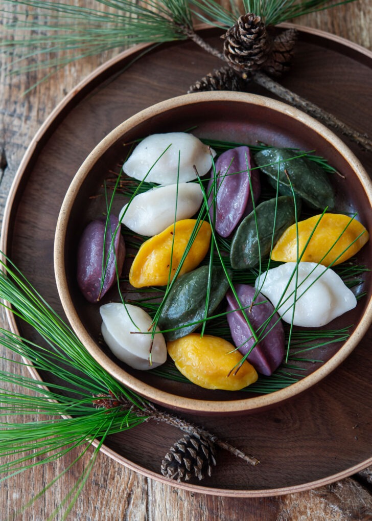 A plate of Korean half-moon rice cake garnished with pine needles.