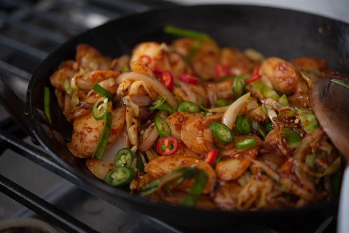Spicy rice cake and vegetable stir-fry in a skillet.