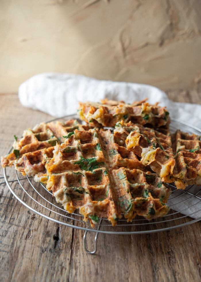 Savory waffles are resting on a wired rack.