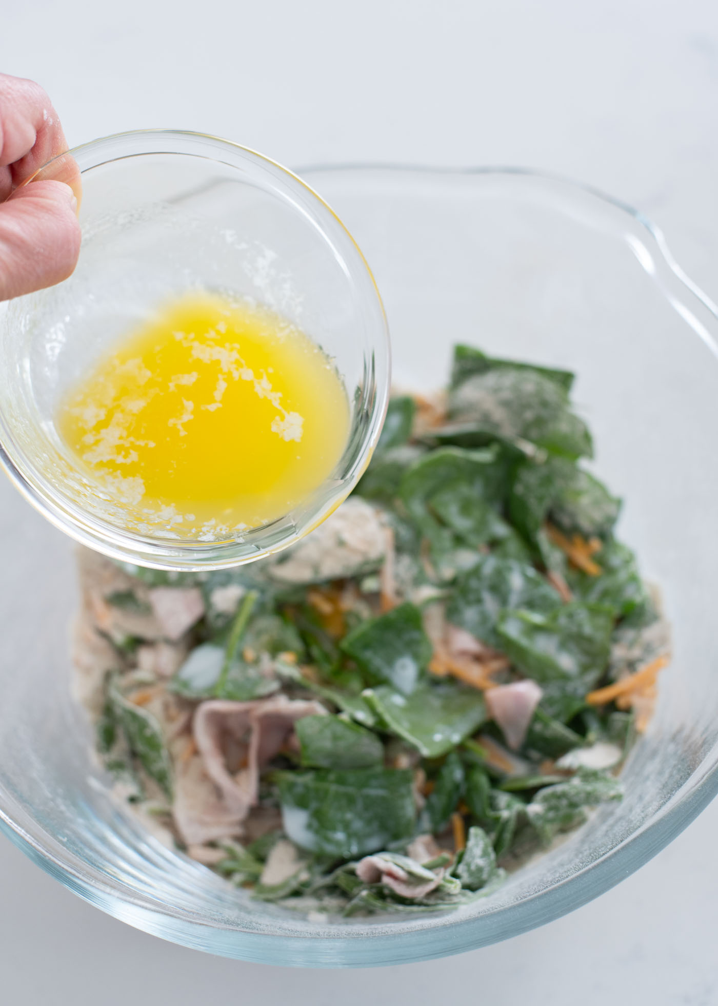 Melted butter is poured on the dry waffle ingredients in a bowl