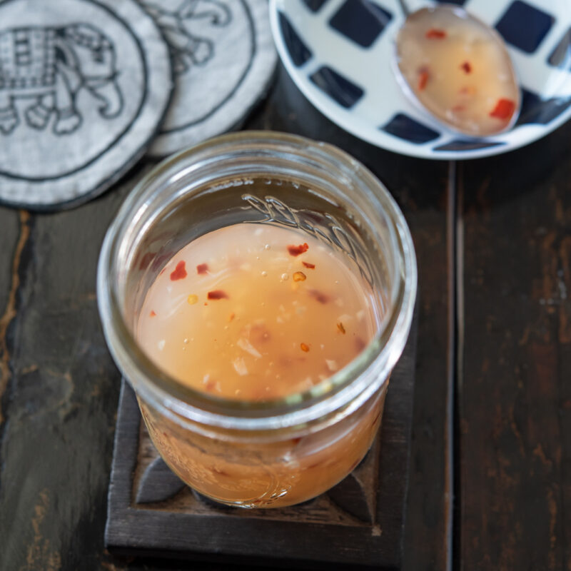 Homemade Thai sweet chili sauce in the jar is showing its light orange color.